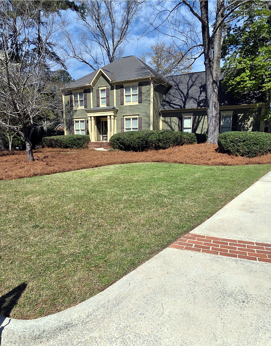 Two-story house with a freshly mowed front lawn, pine straw beds and a brick-trimmed driveway